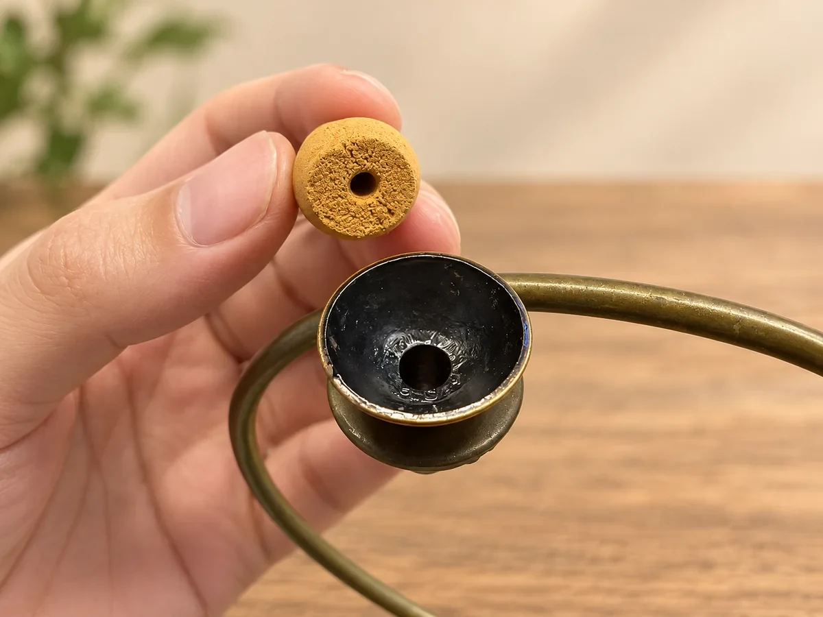 Hand holding a backflow cone above a burner cup to show both openings
